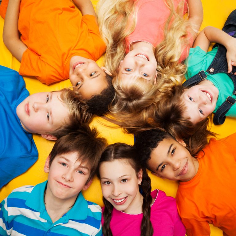 Group of happy kids laying in circle - diversity looking Caucasian and black boys and girls smilng